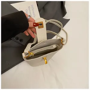 Vista interior del bolso tipo cubo en cuero blanco con compartimentos y herrajes dorados