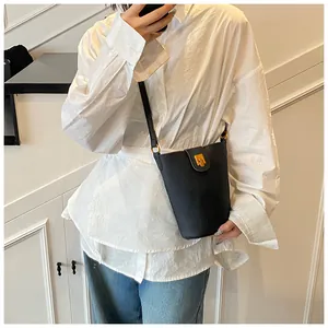 Detalle del bolso tipo cubo negro en cuero granulado con hebilla dorada y correa