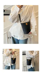 Detalle de bolso bucket en cuero negro con textura lichi, cierre dorado y correa ajustable