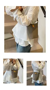 Detalle de bolso cubo en cuero taupe con cierre dorado y logotipo de la marca