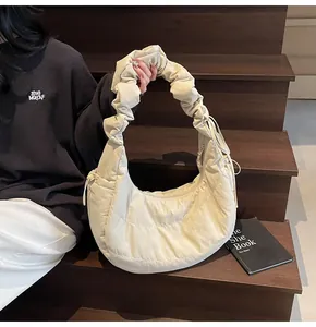 Close-up of beige hobo bag with quilted texture and ruched handle on wooden steps