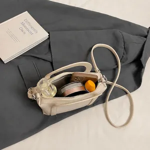 Vista dall'alto della borsa a secchiello crema con dettagli interni e accessori