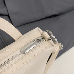 Dettaglio macro della minuteria d'argento e pelle martellata della borsa a secchiello