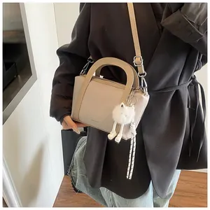 Dettaglio borsa a secchiello beige con trama a grana e charm a forma di gatto peluche