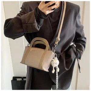 Selfie allo specchio con la borsa a secchiello beige a grana e un ciondolo a cucciolo
