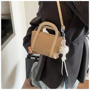 Dettaglio ravvicinato di una borsa beige in pelle martellata con un pompon bianco di peluche