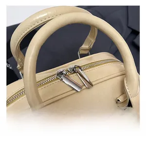 Detailed macro view of the silver zipper and beige leather handles on the Boston bag