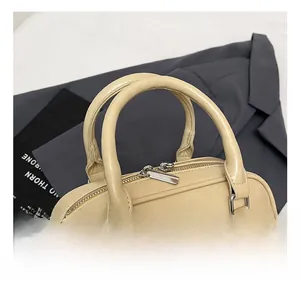 Detail of cream Boston bag featuring sturdy rolled handles and silver zipper hardware
