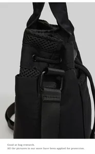 Detail view of black nylon bucket bag with mesh pocket and metal D-ring attachment