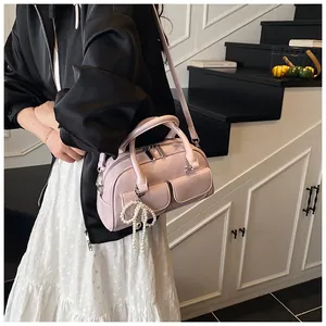 Detail of light pink Boston bag with pearl bow charm and twin top handles
