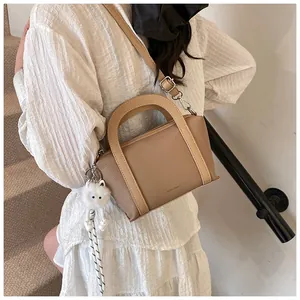 Dettaglio borsa in pelle martellata beige con ciondolo a gatto e finiture argentate
