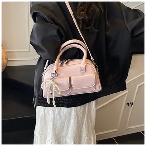 Detail of light pink Boston bag with glossy PU leather and pearl bow charm