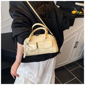 Detail of beige Boston bag with pearl tassel charm and textured leather finish