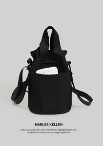 Detail of black nylon bucket bag with drawstring closure and front pocket for mobile storage