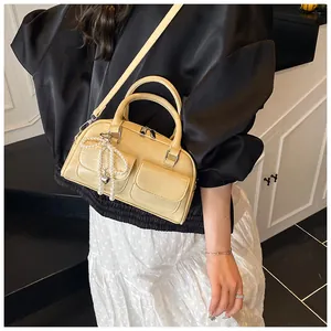 Detail of cream Boston bag with front pockets and pearl heart charm accessory