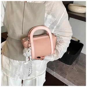 Dettaglio di una borsa a secchiello rosa in pelle con un ciondolo a forma di coniglio