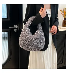 Detail of silver pleated satin hobo bag featuring ruffled texture and metallic finish