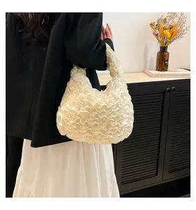 Detail of cream pleated ruffle handbag showing soft satin texture and elegant wavy layers