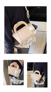 Dettaglio borsa a secchiello beige in pelle martellata con ciondolo e sciarpa a righe