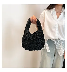 Detail view of the black ruffled pleated handbag featuring soft tiered fabric layers