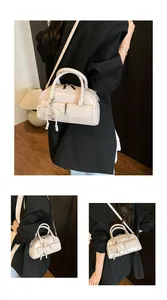 Detailed views of a beige Boston bag with pearl bow charm and adjustable strap