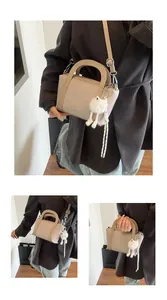 Dettaglio borsa a secchiello beige in pelle martellata con ciondolo a gatto e tracolla