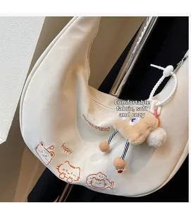 Détail du sac croissant crème avec broderie chat et breloque ours en peluche douce
