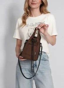Detail of a dark brown canvas drawstring bucket bag with black adjustable shoulder strap