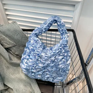 Light blue pleated ruffled tote bag made of glossy satin fabric in a metal shopping basket