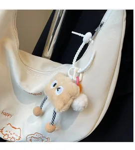 Détail d'un joli pendentif en peluche avec des jambes rayées sur un sac à main blanc