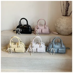 Detail view of mini Boston bags in multiple colors with pearl bow charms and dual pockets