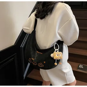 Détail du sac hobo noir avec broderie orange et pendentif ours en peluche mignon