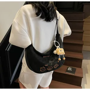 Détail du sac bandoulière en forme de croissant noir avec broderie chat et peluche
