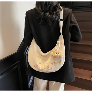 Détail du sac dumpling en toile crème avec broderie chat et pendentif pain en peluche