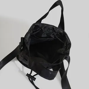 Versatile black nylon drawstring bucket bag with adjustable shoulder strap for yoga and sports