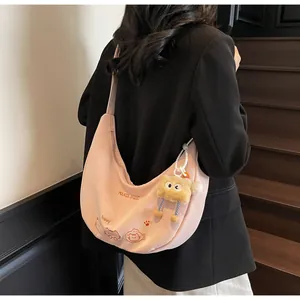 Détail du sac demi-lune rose avec broderie chat et pendentif peluche monstre