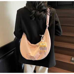 Détail du sac demi-lune rose avec broderie chat et pendentif monstre en peluche sur la bandoulière