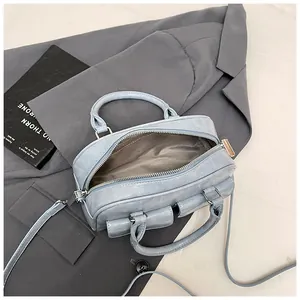 Light blue faux leather Boston bag with double handles and adjustable shoulder strap