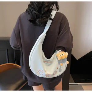 Détail du sac demi-lune bleu clair avec broderie chat dessin animé et pendentif en peluche