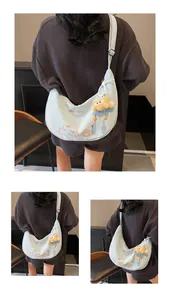 Détail du sac croissant en toile bleu clair avec motifs de chat et charme en peluche