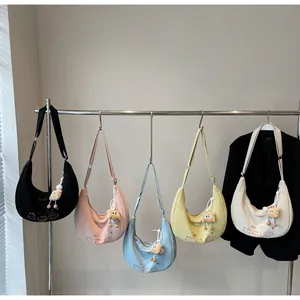 Détail de cinq sacs croissants colorés avec broderies cartoon et breloques en peluche