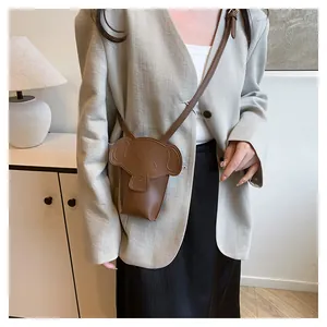 Detail of the elephant-shaped crossbody bag in brown leather on a beige blazer outfit