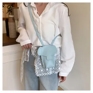 Light blue elephant crossbody bag styled on a model wearing white shirt and jeans