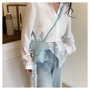 Detail showing a light blue elephant-shaped mini crossbody phone bag on a model