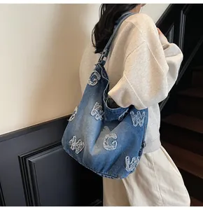 Macro view of retro washed blue denim tote bag featuring frayed letter patchwork detail