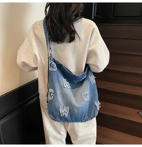 Detailed back view of a blue denim tote bag featuring vintage frayed letter patches