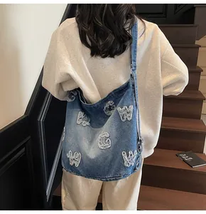 Detailed back view of a blue denim hobo bag with white vintage patchwork on a model