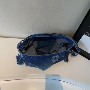 Distressed blue denim tote bag with oversized interior and vintage streetwear aesthetic