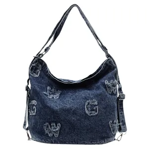 Distressed dark blue denim hobo bag with frayed patchwork letters and wide shoulder strap