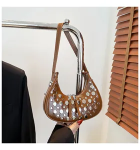 Détails des rivets argentés sur le sac croissant en cuir marron poli et chic